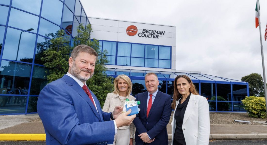 Men and women stand in front of a Beckman Coulter Diagnostics building in County Clare, Ireland.