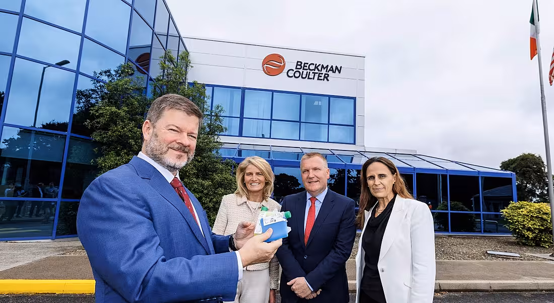 Men and women stand in front of a Beckman Coulter Diagnostics building in County Clare, Ireland.