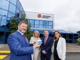 Kerry TD Brendan Griffin pictured with the TLI Group engineering team at the opening of its new office. A group of engineers standing and sitting in formation outside a large brown bricked building.