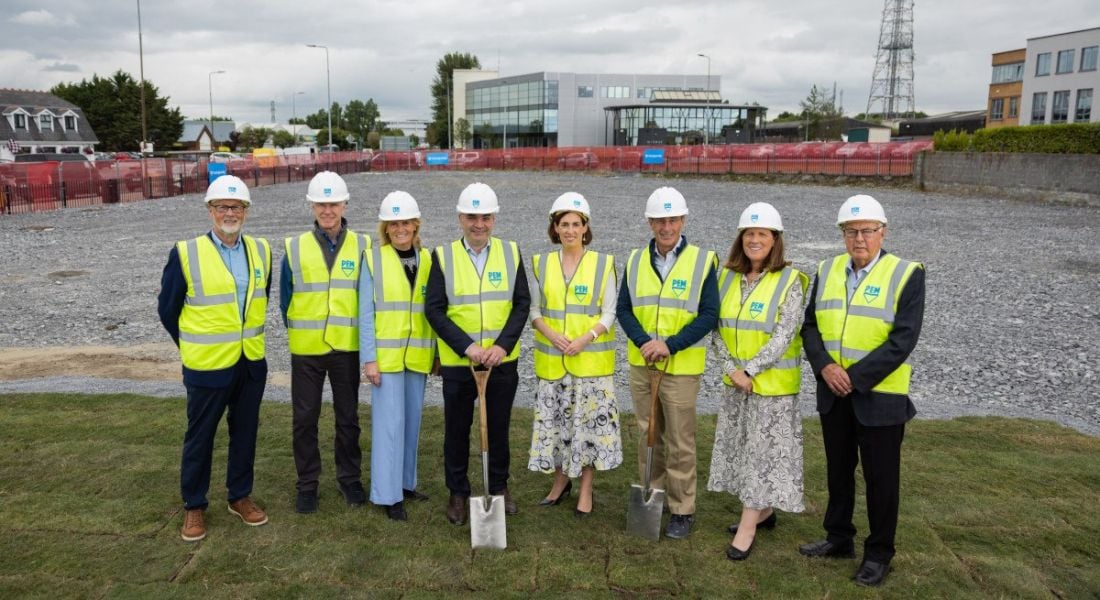 A group of people wearing construction outfits and helmets stand in front of a PennEngineering site in Galway.