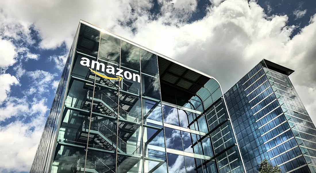 An image of an Amazon building against a blue and cloudy sky.