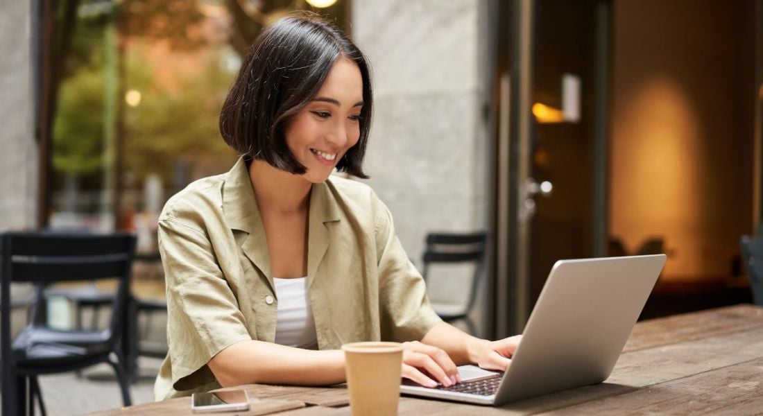 An Asian woman is working in a cafe, accessing the internet on her device via a public network.