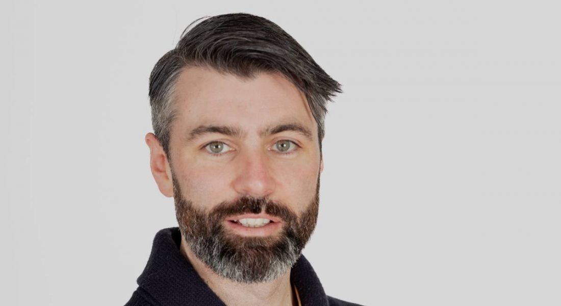 A headshot of a man smiling in front of a white background. He is Eoghan Powell of Work IQ.