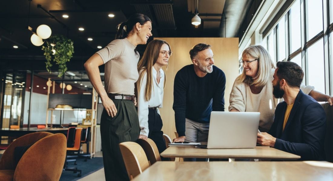 Several people in an on-site working environment crowd around a man showing camaraderie and friendship at work.