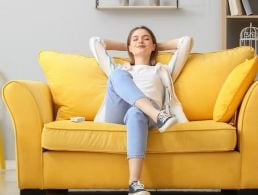 A young woman sitting on a couch working on a laptop, symbolising flexible working.