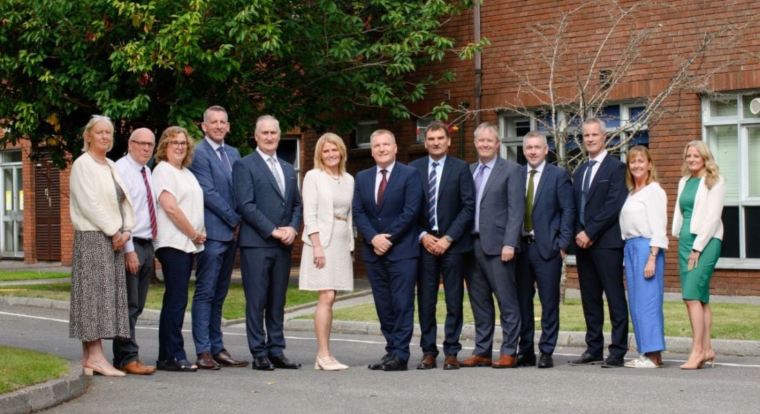 Multiple men and women standing in a row in front of a Cara Partners facility.