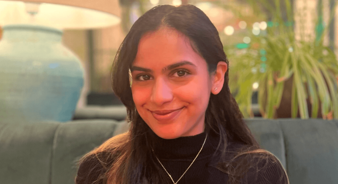 Fidelity Investments' Aparna Pandey sits in front a large green plant in an office.