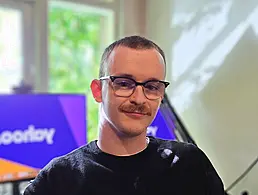 A man sits in a room with a whiteboard and a wall behind him. He is Mark Stewart, a software architect at Yahoo.