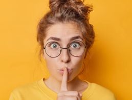 College student has her back to the camera and is facing away, punching her hand into the air to show scholastic success.