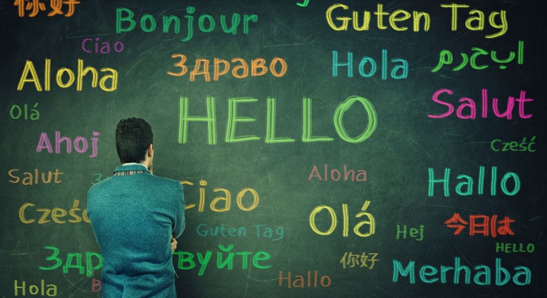 A man faces a board with the word hello spelt out in multiple different languages.