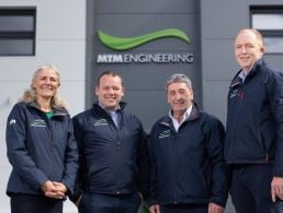 Multiple men and women standing in a row in front of a Cara Partners facility.