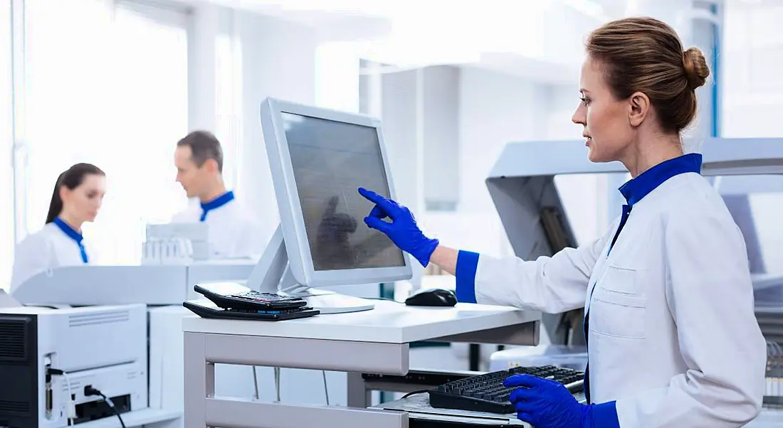 Life sciences workers in a lab looking at a computer.