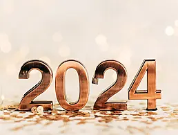 Person's hand turning a cube on a calendar from 2023 to 2024. Blue background.