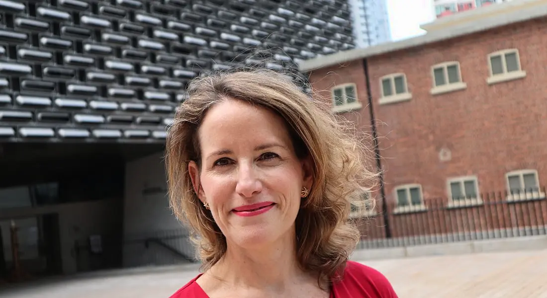 A woman standing outside a building and smiling. She is Diana Wu David.