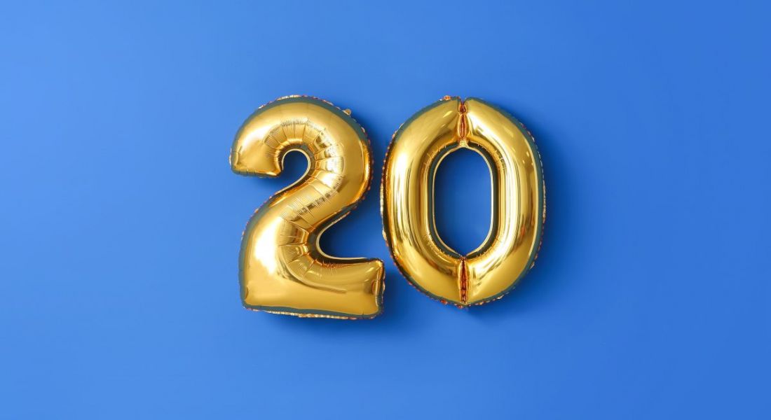 Two gold balloons in the shape of the number twenty on a blue background.