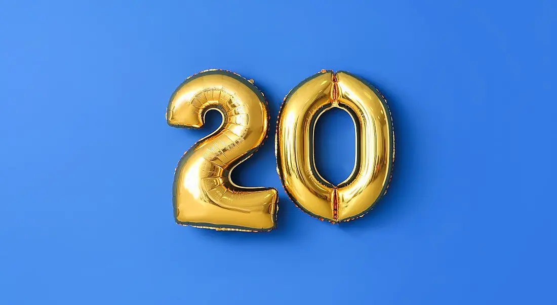 Two gold balloons in the shape of the number twenty on a blue background.