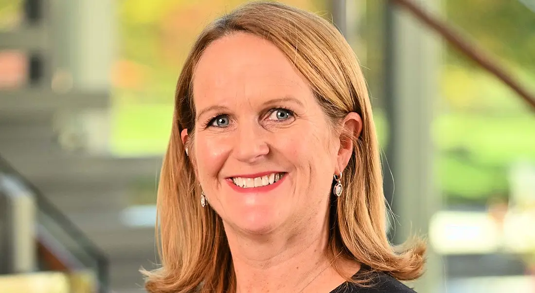 Headshot of Aileen Kinsella of West pharma with a blurry room visible in the background.