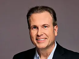 A headshot of Workhuman's Shmulik Barel smiling at the camera in a bright office.