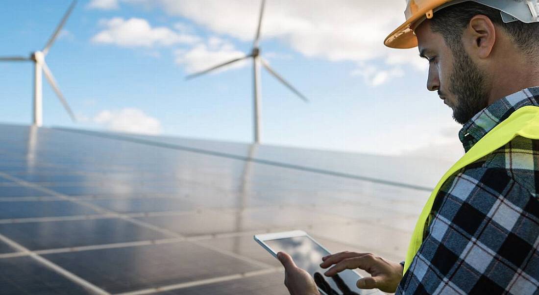 A young man working with digital tablet at renewable energy farm.