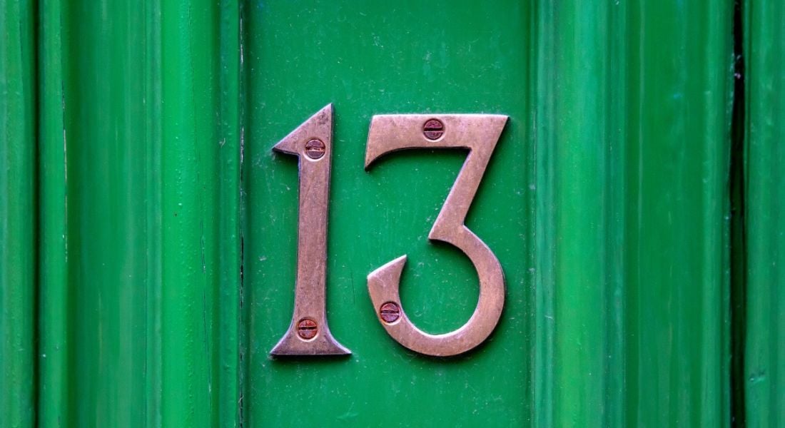 The number 13 screwed into a green front door, representing the number of AI influencers on this list.