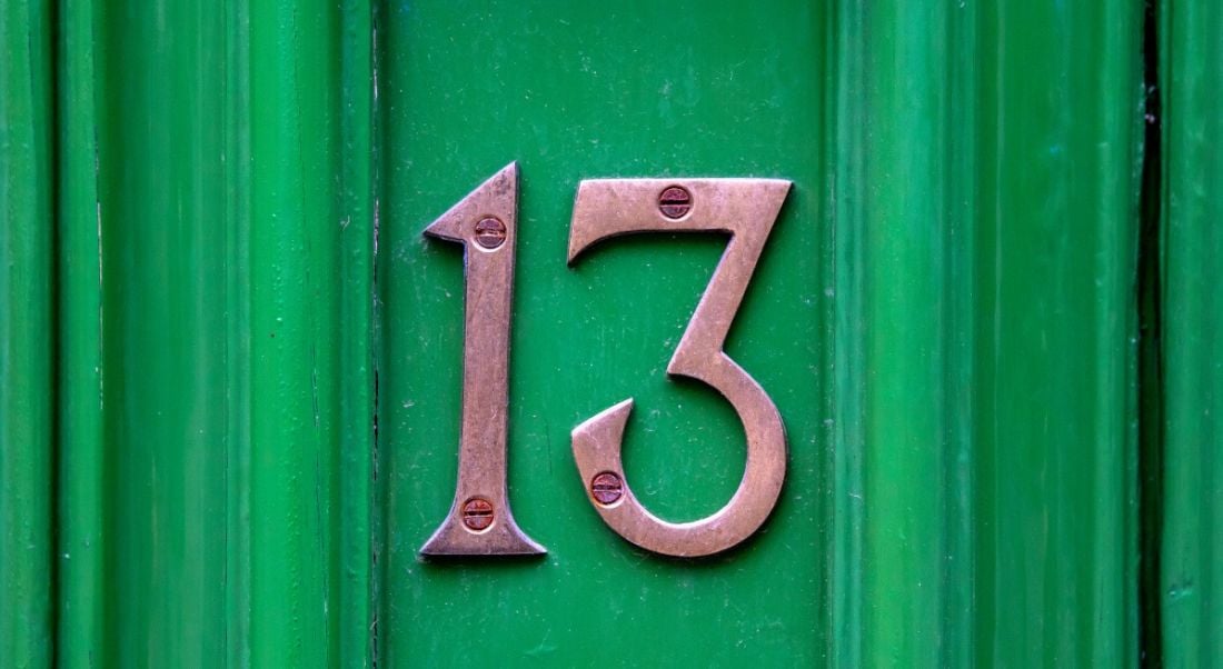 The number 13 screwed into a green front door, representing the number of AI influencers on this list.