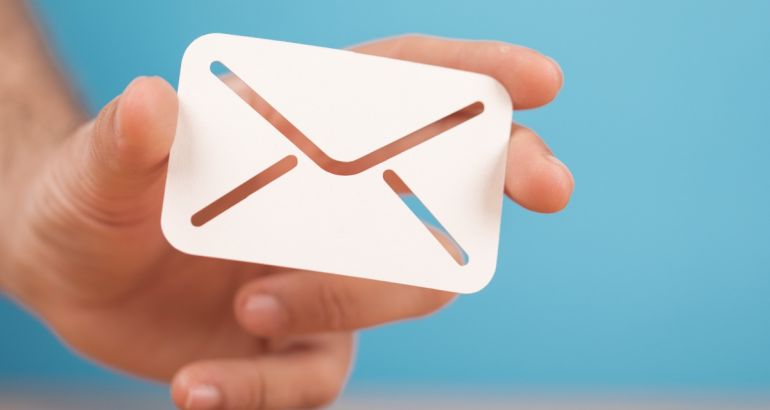 A hand holding a white email icon envelope against a blue background.