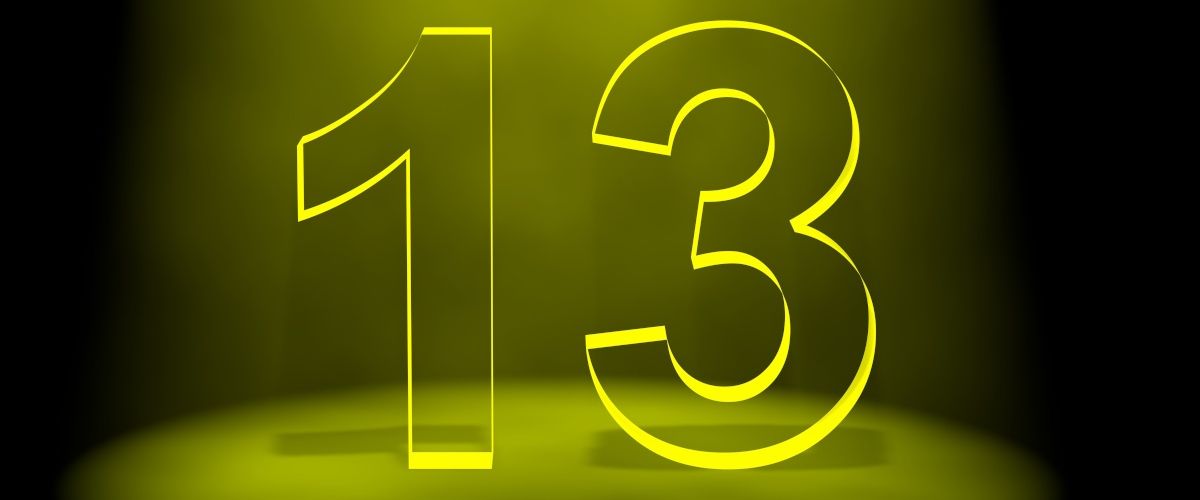 The number 13 in black lit up by yellow light on a black background.