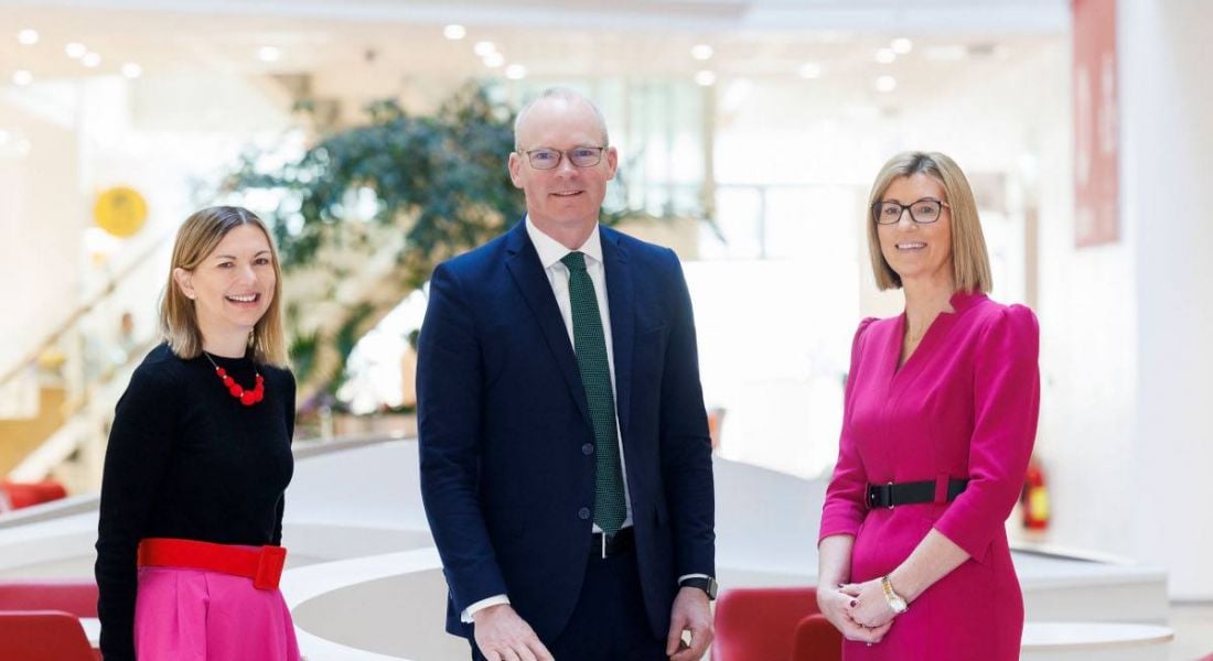 Two women from Vodafone Ireland and Irish Minister Simon Coveney standing together in a room.