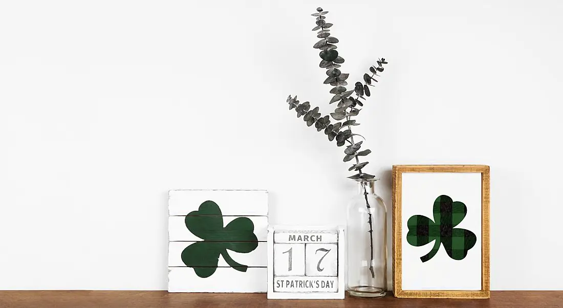 A calendar with the date 17th of March sits on a desk next to two drawings of a shamrock and a thin plant.