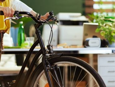 A woman bikes to work for workplace green initiatives.