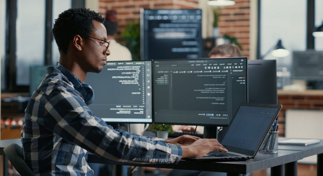 A man sits at a computer working on his role as a software engineer.