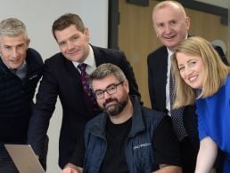 A woman in a green blazer leans on a grey wall in front of an out-of-focus window. She is the MD of Optum UK and Ireland.