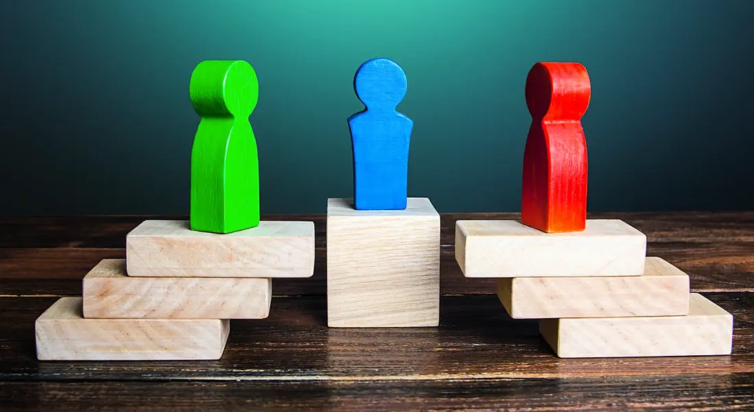 A red, blue and green piece, stands atop a wooden block, indicating the resolution of conflict at work.