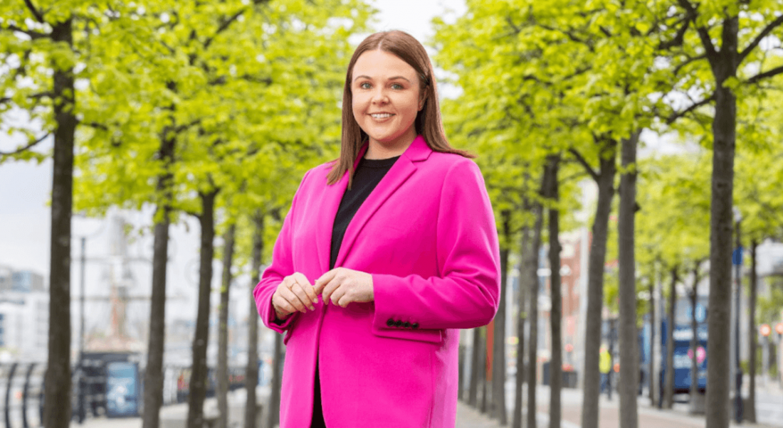 Rebecca Keenan posing in a pink blazer, outside.