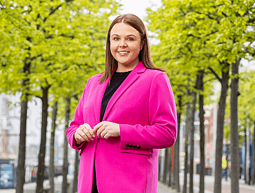 Rebecca Keenan posing in a pink blazer, outside.