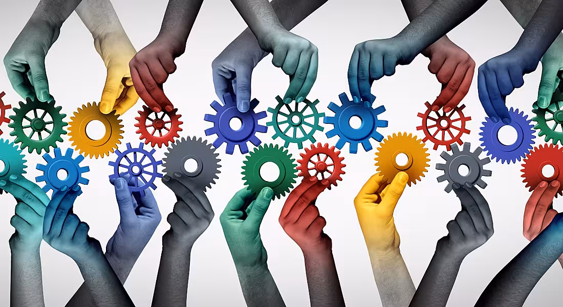 Hands holding multicoloured wheels represent diverse team culture and collaboration.