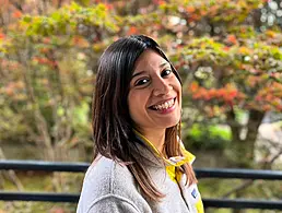 Camelia Farcas, associate software engineer at Fidelity Investments, is standing in a corporate setting and looking into the camera.