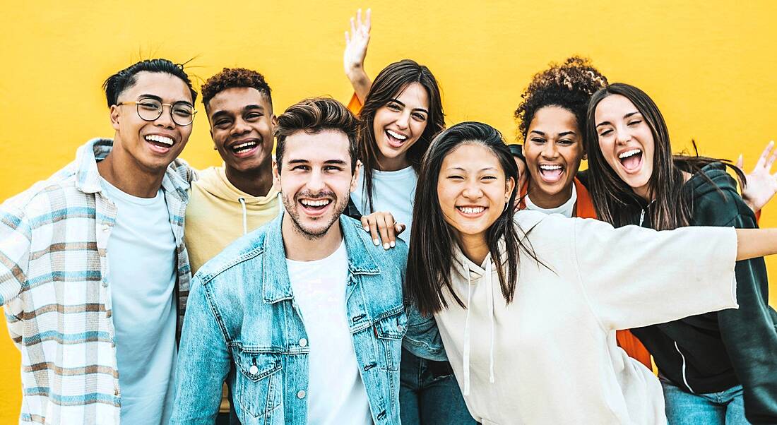 Multiracial group of young people laughing looking at the camera.