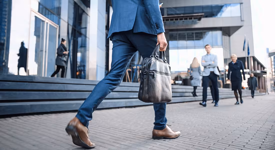 A man in a suit with a briefcase walking into his workplace.
