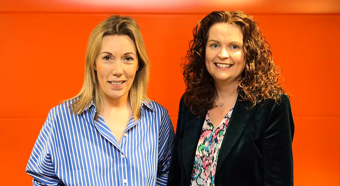 Fidelity Investments Karen Conway and Eimear Coffey, stand against an orange background.