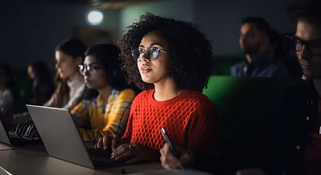 A young black woman in red sits in a lecture learning skills.