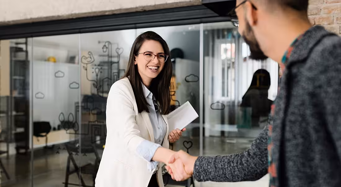 A woman shakes a man's hand, indicating he has been given a new job.
