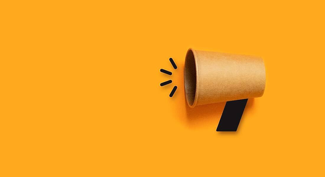 A cardboard megaphone against a dark yellow background.