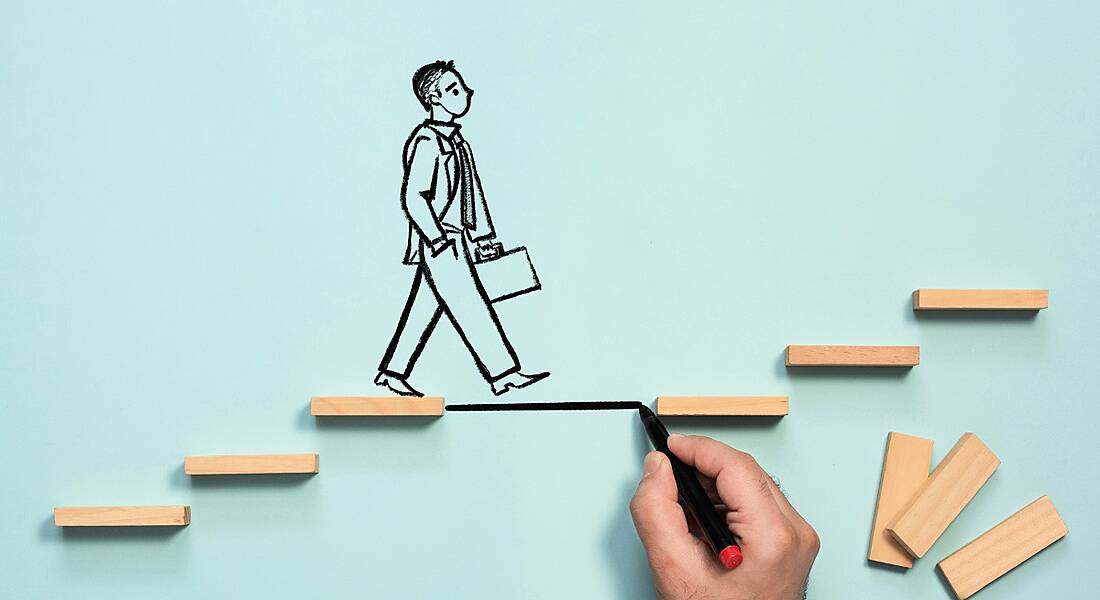 Business person drawn on a blue background with a hand drawing a step to fill a gap in the stairs he is walking up.