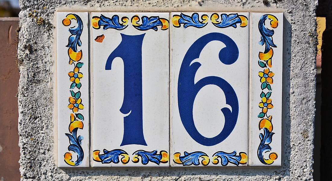 Number 16 printed on tiles on a white wall.