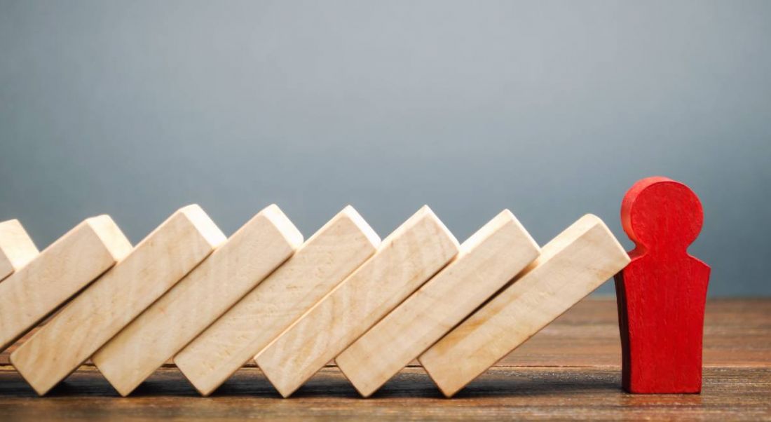 Wooden dominoes are falling against a red wooden figure.