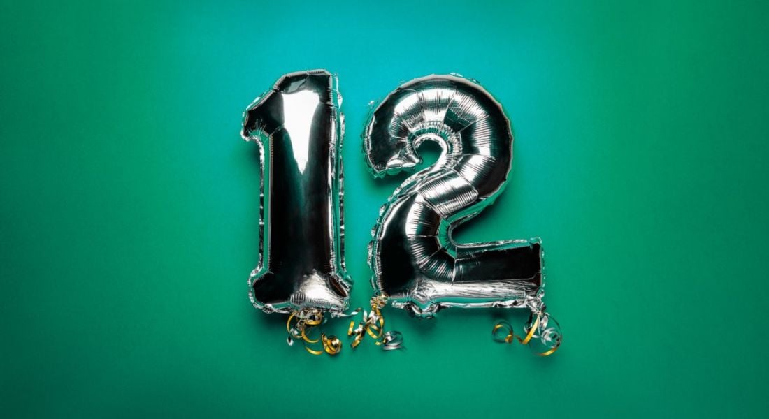 Silver foil balloons in the shape of the number 12 against a deep green background.