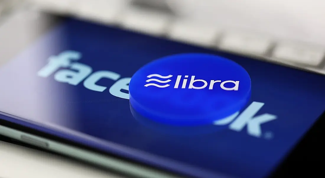 Badge with Libra logo on a phone with the Facebook logo on screen.