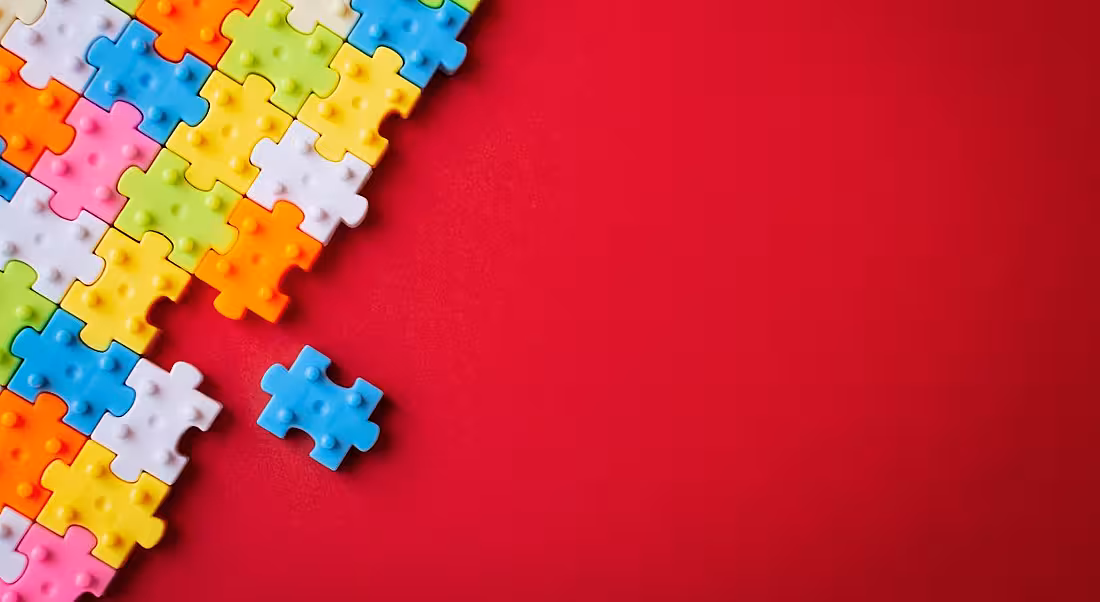 Colourful plastic jigsaw puzzle on red background.
