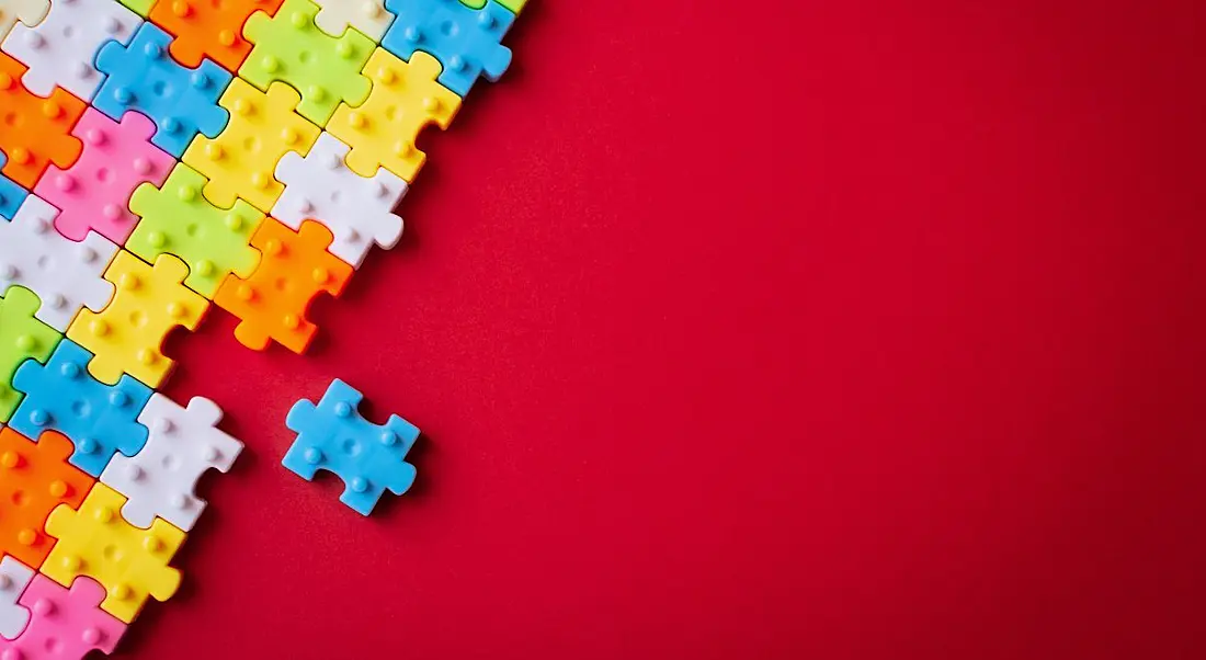 Colourful plastic jigsaw puzzle on red background.